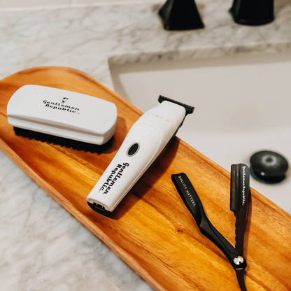 Grooming products: trimmer, brush, and scissors on a wooden tray 